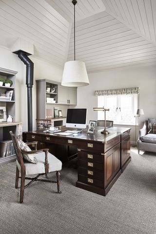 home office with wooden desk in middle and tall ceilings
