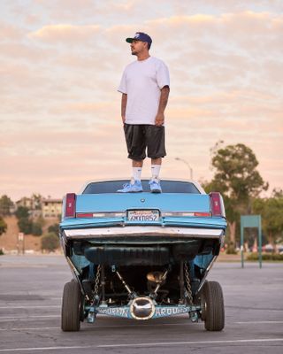 A man standing on top of a Cutlass car in Pasadena California