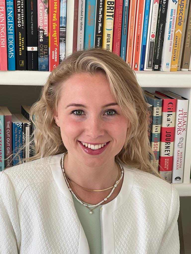 A headshot of Laura Honey, with bookshelves in the background