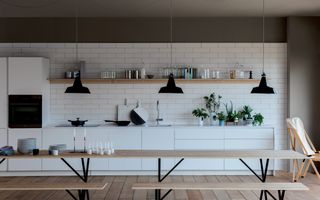 white scheme kitchen with light woods and hanging lights by schiffini