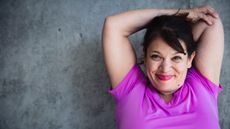 A woman crosses her arms behind her head and grasps her left elbow with her right hand