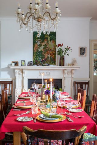 dining table with red cloth and christmas details with period fireplace behind