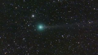 An image of star-filled space with a green comet shooting through the field of view