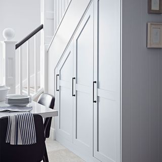 grey under stairs storage cupboards, with a dining table next to them