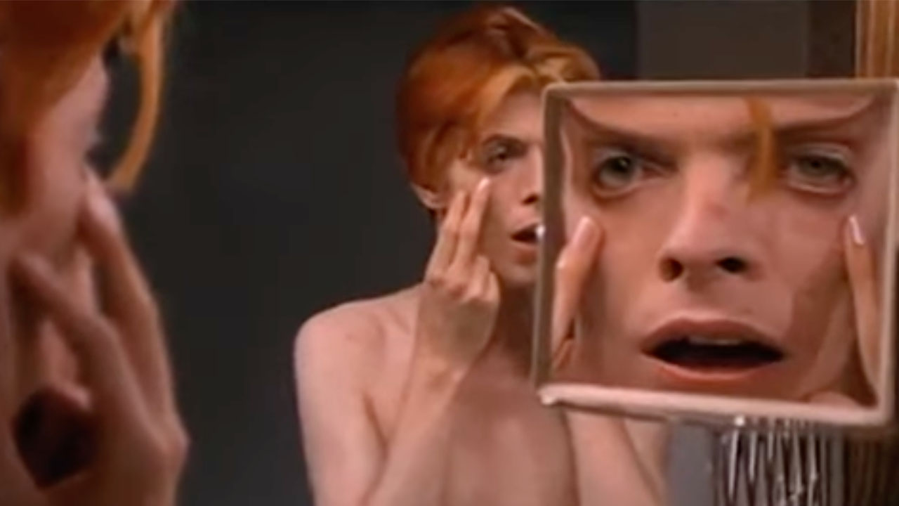 David Bowie looking at himself in a mirror and touching his face in the Man Who Fell to Earth.