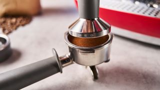 a red smeg espresso machine with burr grinder is photographed against a blue background