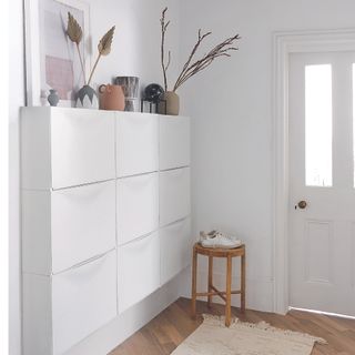 White hallway with shoe storage and plants.