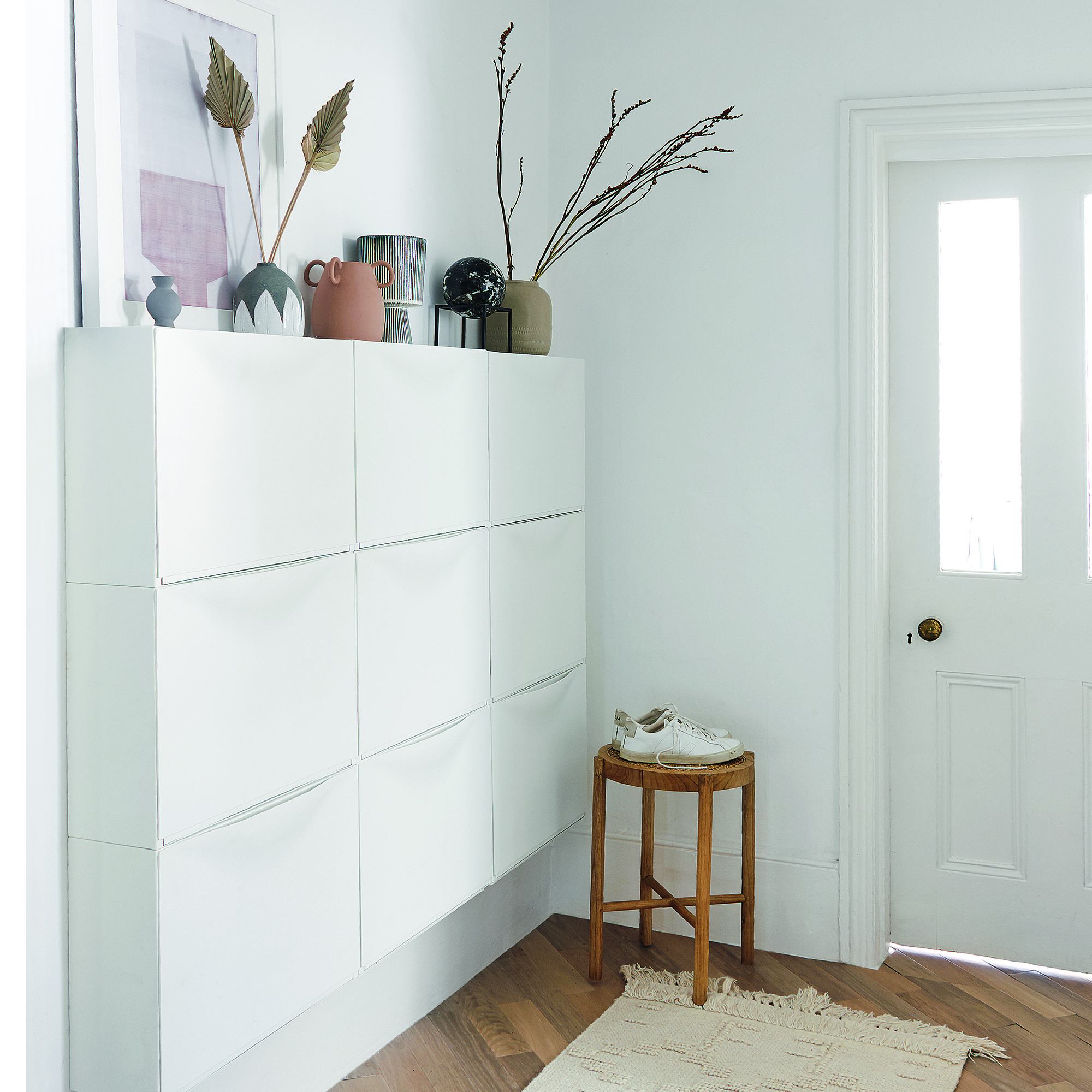 White hallway with shoe storage and plants.