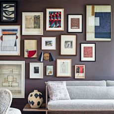 Living room with a sofa and chair, carpet on wood floorboards and a gallery wall full of artworks