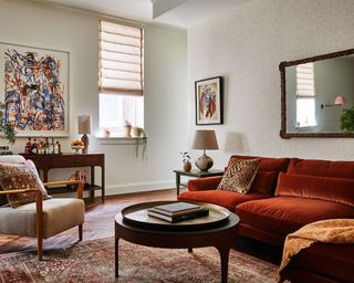 Living room with amber color sofa, neutral armchair, neutral walls and wood console, side and coffee table