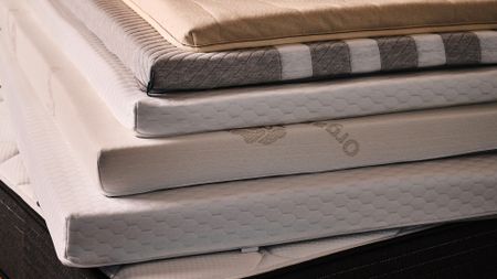A close up of a stack of mattress toppers of different designs and thicknesses