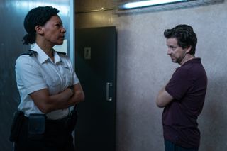 Leigh (Nina Sosanya) stands inside a room at the prison with inmate Patrick Morgan (Lee Ingleby). She looks frustrated and her arms are folded. He is facing her and has one arm across his chest with the hand resting on his other shoulder.