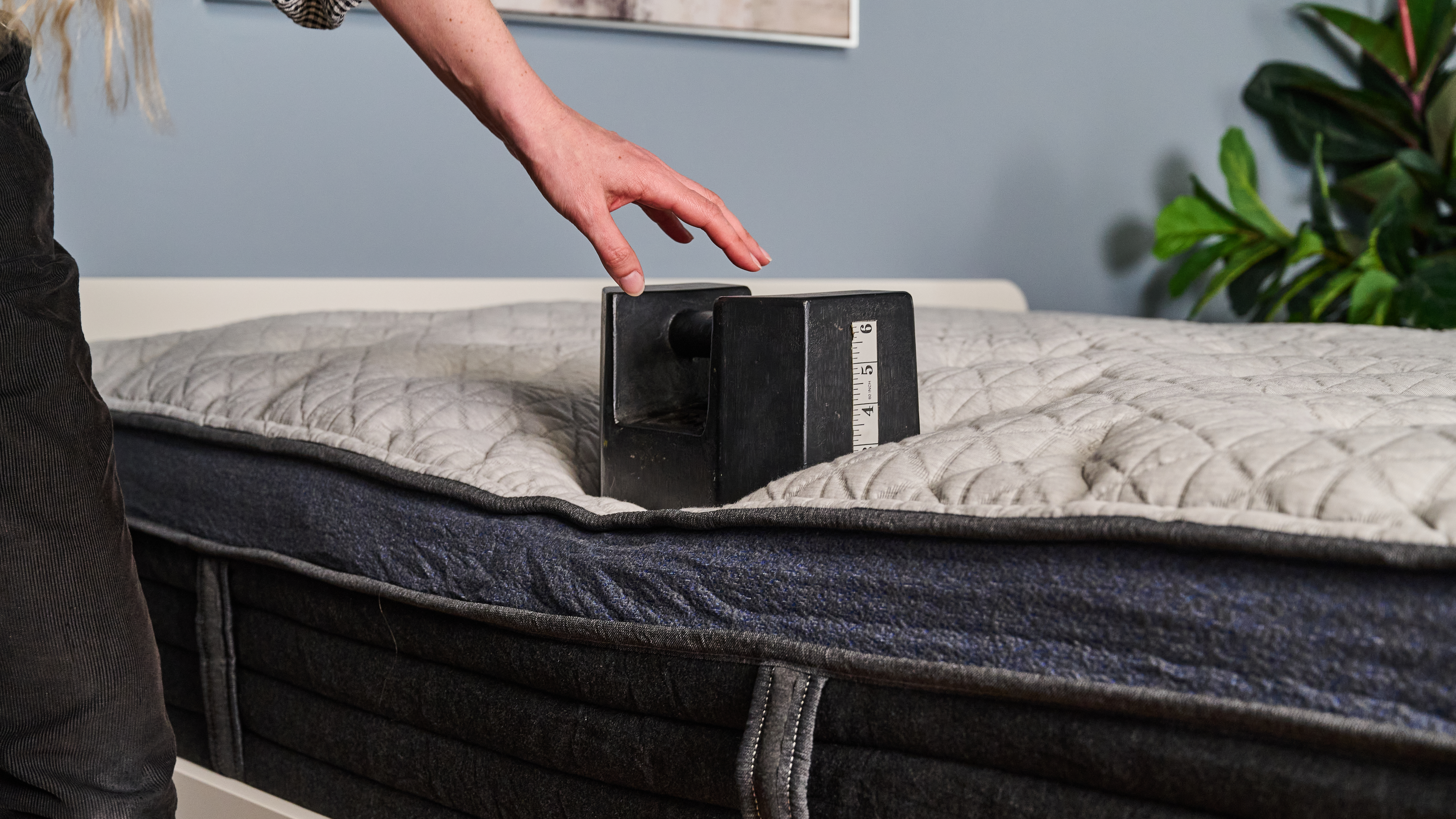 The image shows a mattress tester placing a 56lb weight on the edge of the Helix Midnight Luxe to test its edge support