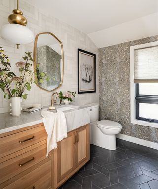 bathroom with wooden vanity, gray tiled flooring, neutral wallpapered accent wall