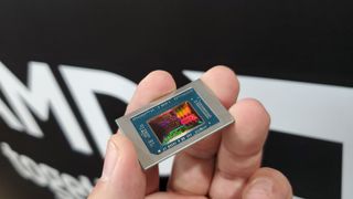 AMD Strix Point APU chip, held in a hand, with the reflected light showing the various processing blocks in the chip die