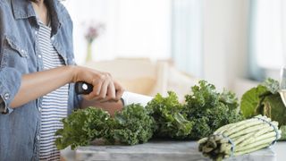 A woman in a kitchen chopping magnesium-rich kale