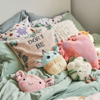 Bed with cushions and plush toys spread on top