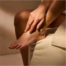 a close up image of a person rubbing lotion onto their foot