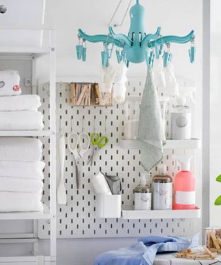 peg board with shelving in a small laundry room with blue clothes dryer, shelving and ironing board