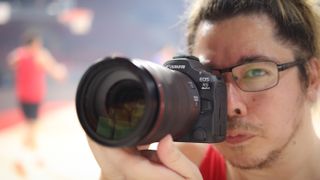 Photographer James Artaius using a Canon EOS R5 Mark II in front of a basketball game