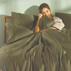 Person snuggling a duvet in a bed