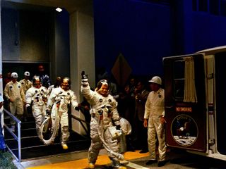 The Apollo 11 crew leaves Kennedy Space Center's Manned Spacecraft Operations Building during the pre-launch countdown. Mission commander Neil Armstrong, command module pilot Michael Collins, and lunar module pilot Buzz Aldrin prepare to ride the special transport van to Launch Complex 39A where their spacecraft awaited them. Liftoff occurred at 9:32 a.m. EDT, July 16, 1969.