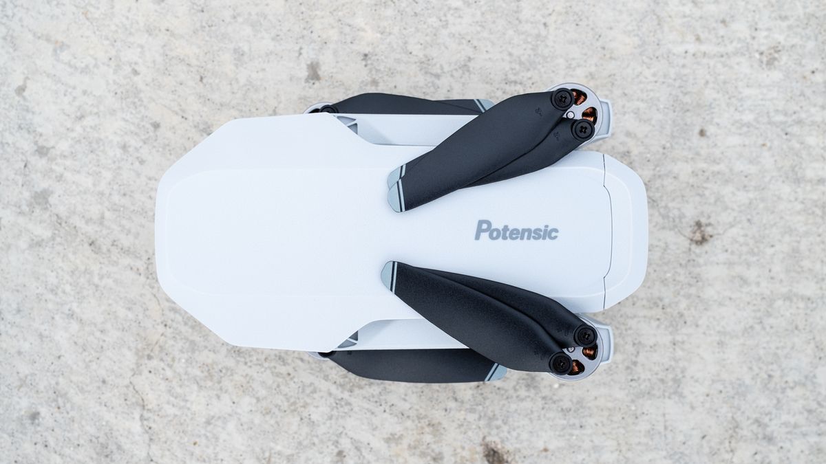 the top-down view of a white, folded drone with black propeller blades.