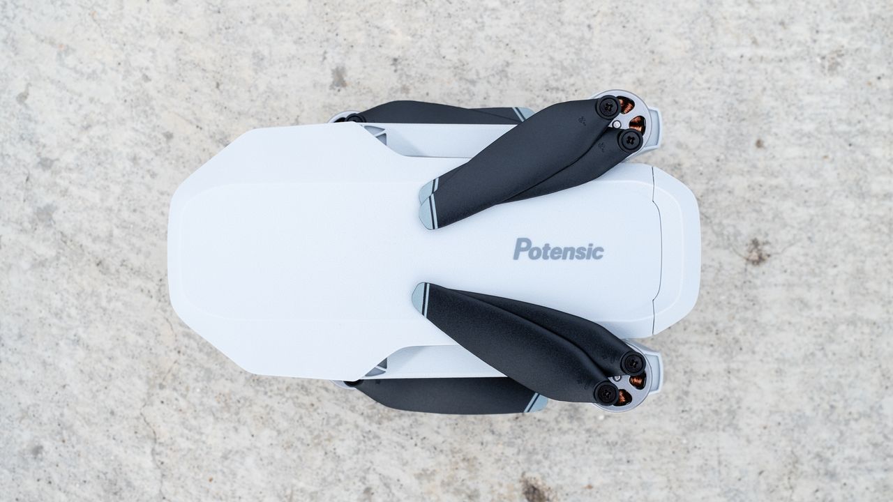 the top-down view of a white, folded drone with black propeller blades.