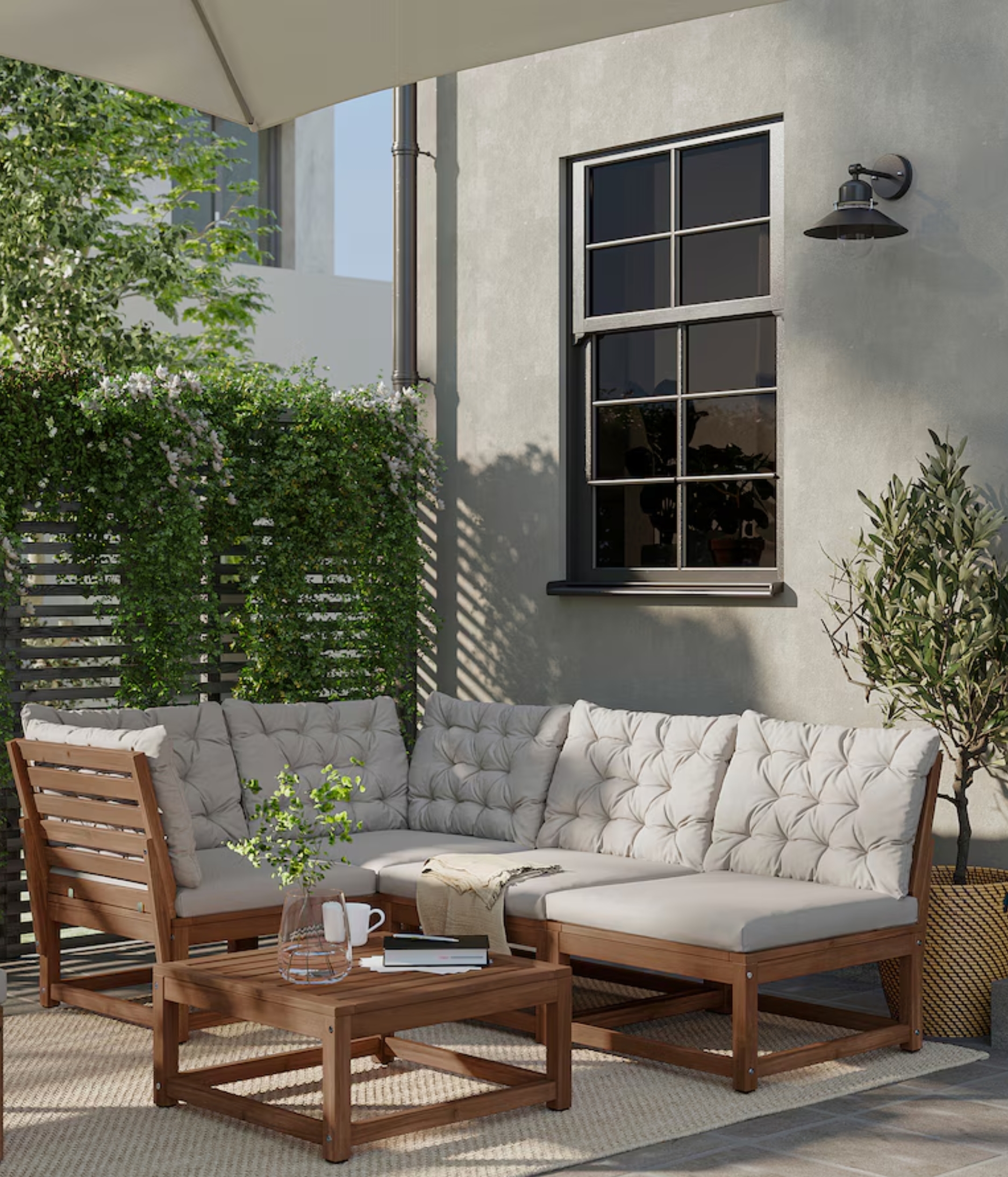 acacia wood outdoor furniture on a patio outside a house next to a fence with plants climbing over it