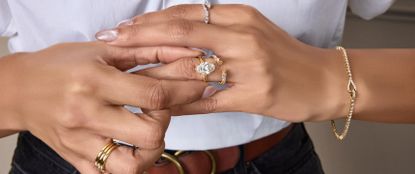 Woman's hands wearing lots of gold jewelery, including a diamond ring