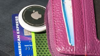 An Apple AirTag partly inserted into a woman's wallet.