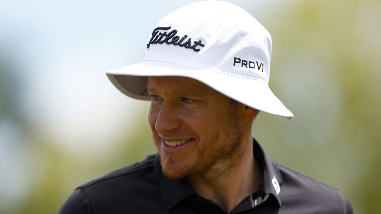 Peter Malnati headshot wearing black polo and white Titleist bucket hat