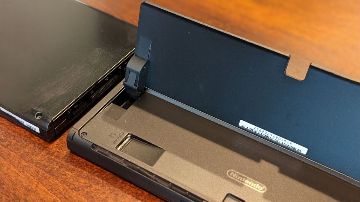 Nintendo Switch OLED with kickstand up and microSD card slot exposed.