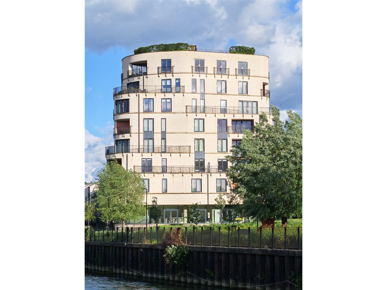 A tall block of flats by a river at a 4x zoom.