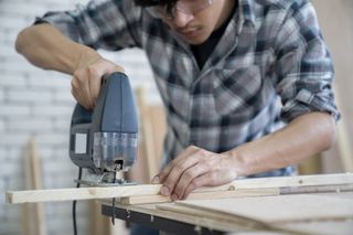 diy tips: a man cutting wood on a workbench