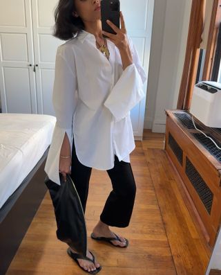 @shayinjune wearing a white button-down shirt, black cropped pants, flip flops, and a black clutch.