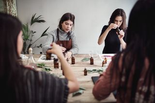 Four women are sitting together a workshop creating perfumes.