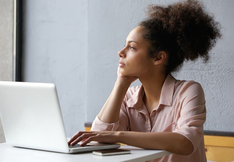 A woman daydreams while sitting at her computer