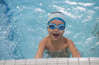 Little boy wearing a swimming hat and goggles in the pool