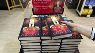an employee of waterstones poses with a copy of the silkworm by author robert galbraith, aka harry potter author j k rowling, as it goes on sale for the first time at a bookshop in london on june 19, 2014 j k rowling published her second crime novel on june 19 under the pen name of robert galbraith afp photo justin tallis photo credit should read justin tallisafp via getty images