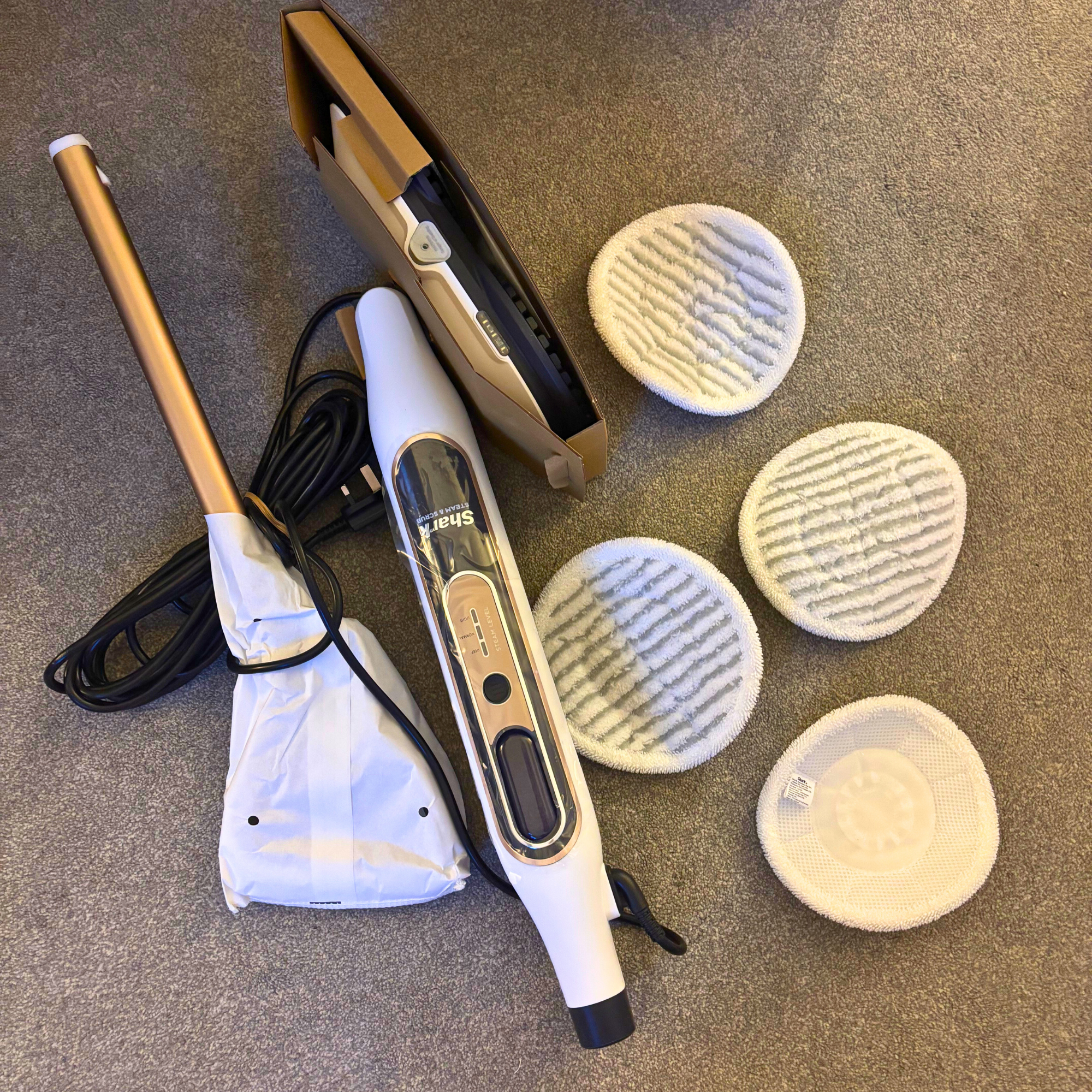 Flatlay of Shark Steam & Scrub parts and accessories on grey carpet