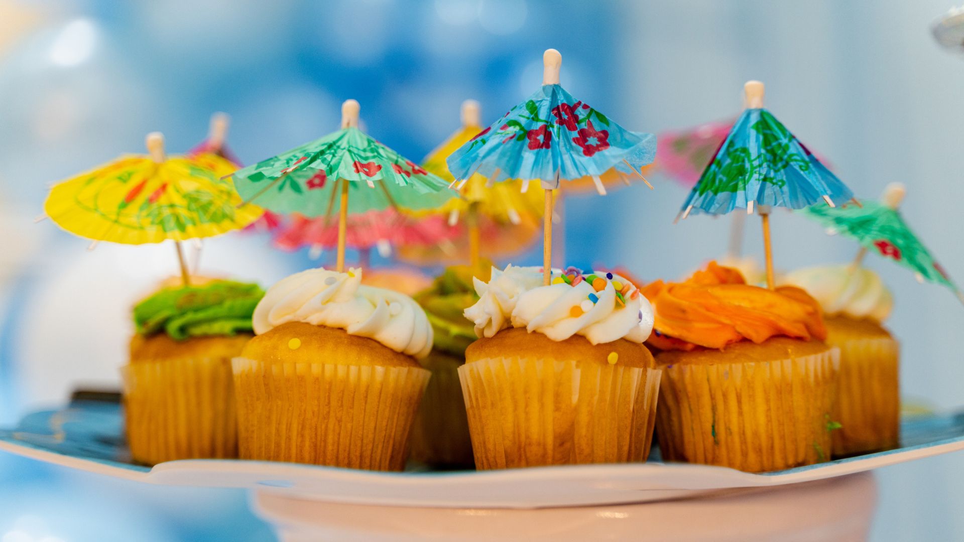A plate full of cupcakes with cocktail umbrellas