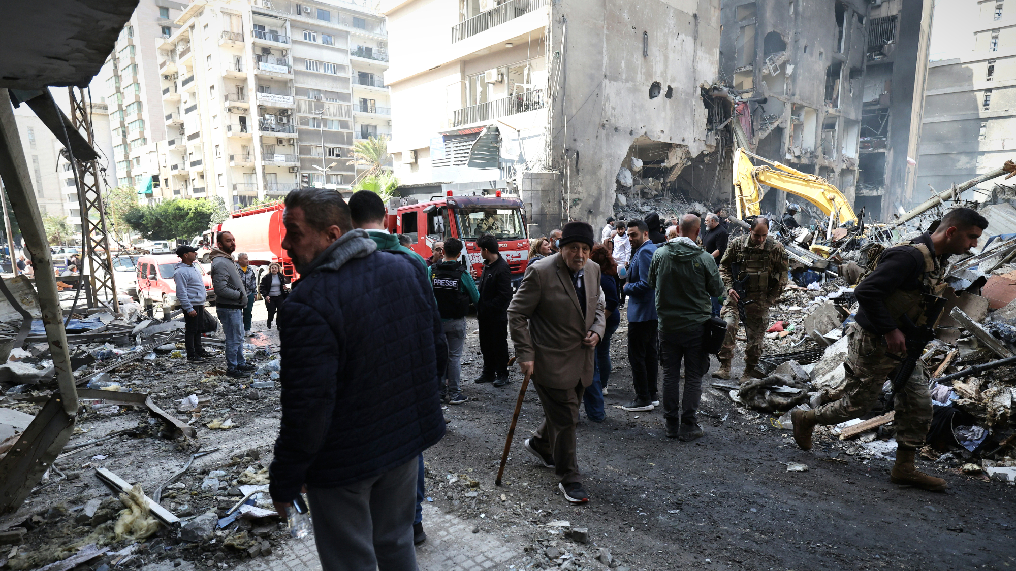 Rescuers and residents walk past destruction at the site of an Israeli airstrike that targeted a building the day before in Beirut