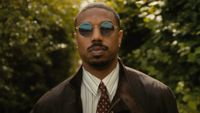 Michael B. Jordan wearing glasses outside in The Thomas Crown Affair