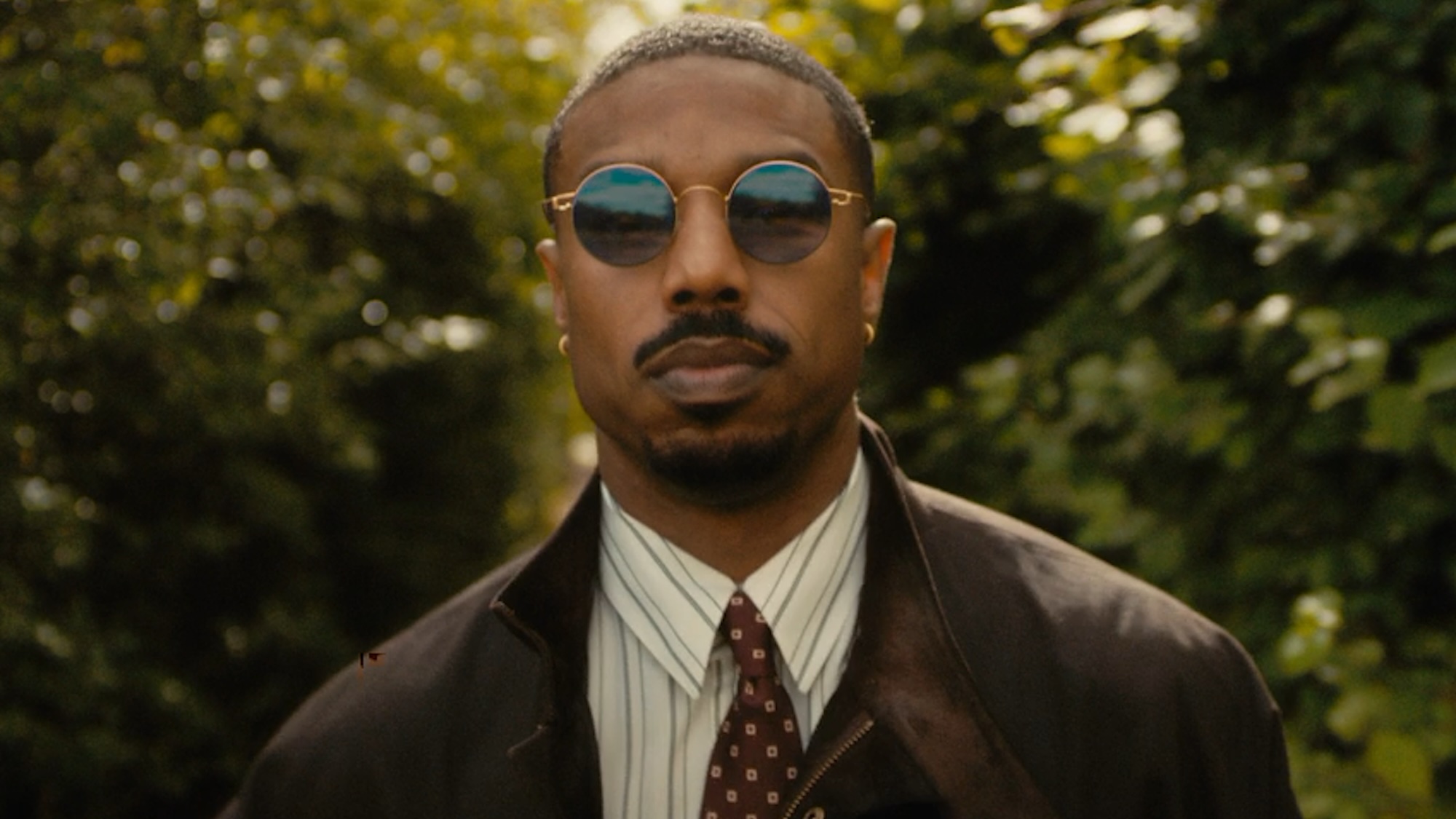 Michael B. Jordan wearing glasses outside in The Thomas Crown Affair