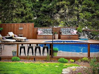 Above ground pool with fencing, bar stools and seating around it
