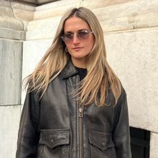 Editor Eliza Huber wears brown leather jacket with 90s-style sunglasses.