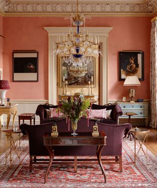 Red living room with antiques, chandelier and wood dining table