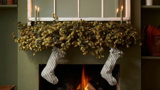 green festive mantlepiece with dried hops, candles and stockings