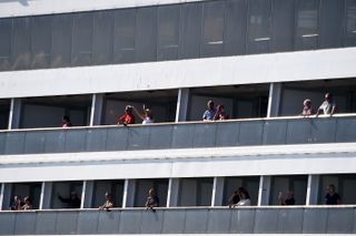 Passengers form Holland America's cruise ship Rotterdam cheer as they head to dock at Port Everglades in Fort Lauderdale, Florida, on April 2, 2020.